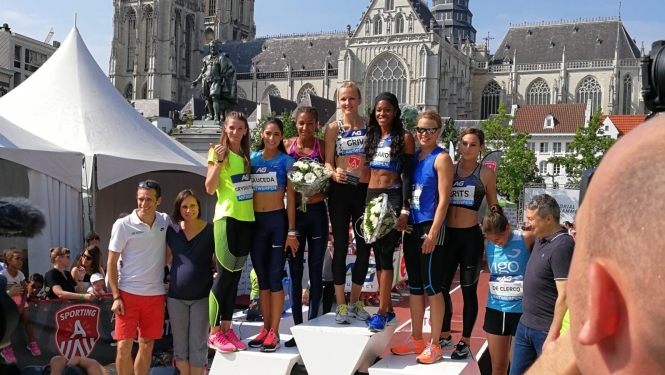 Sportistes stāv uz goda pjedestāla pēc sacensībām pilsētas laukumā pie vēsturiskas baznīcas