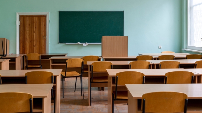 Tukša mācību klase ar soliem, krēsliem un tāfeli pie sienas