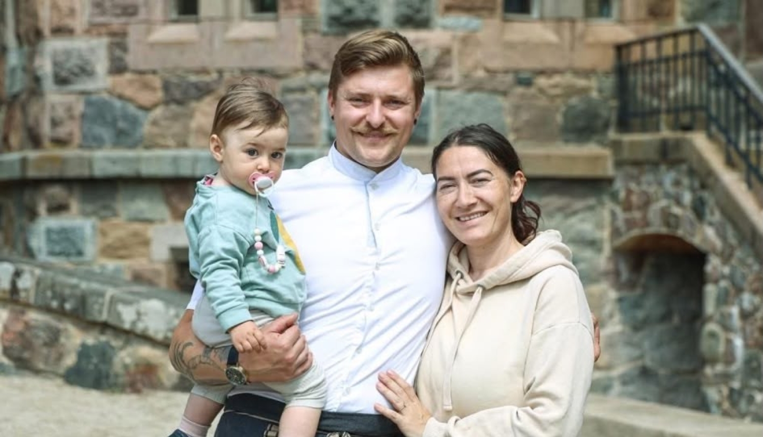 Šefpavārs Juris Latišenoks kopā ar dzīvesbiedri Lindu un mazo meitiņu pozē pie vēsturiskas akmens ēkas