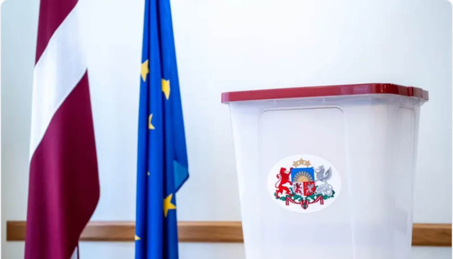 Attēls ar Latvijas un Eiropas Savienības karogu un vēlēšanu biļetenu urna.